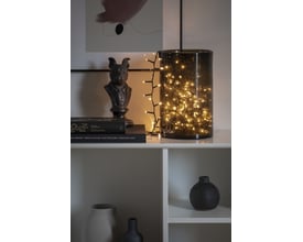 Konstsmide lyskæde med 200 varmhvide LED'er, pyntende en mørk glasvase med bobleeffekt.