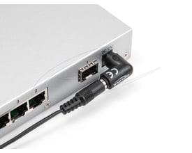 DeLock 90° DC-adapter med 5,5 x 2,5 mm stik sidder tilsluttet DC-indgangen på et apparat.