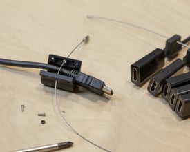 Deltaco HDMI pigtail adapterring i sort med fem forskellige stik, herunder USB-C, DP, Mini DP, Mini HDMI og Micro HDMI, på et træbord.