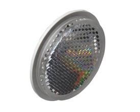 Carlo Gavazzi prismereflektor Ø46 x 6,5 mm til påklæbning med rund grå kant og facetteret refleksflade, set skråt forfra.
