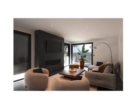 SLV One Bow FL standerlampe i sort stål, vist i et moderne loungeområde med sofaer og et stort vindue.