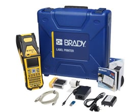 Brady M610 labelprinter med QWERTY-tastatur og Bluetooth ses sammen med blå transportkuffert og tilbehør.