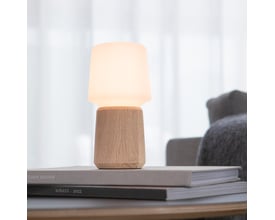 SACKit Base Oslo eg lampefod på 84 mm, samlet med en lampeskærm og placeret på en bog i en stue.