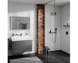 Moderne badeværelse med Hansgrohe håndbruserslange i sort monteret på en bruseniche med hvide fliser og en rustik murstensvæg.