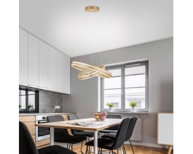Q-Vito LED pendellampe i messing monteret over et spisebord i et moderne køkkenmiljø, med lyset tændt.