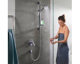 Hansgrohe Crometta Vario Unica brusesæt i krom viser brusehoved med vand, en bruseslange og en kvinde i et brusekabine.
