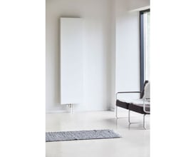 Stelrad Vertex Plan radiator H2200 T11 L600, hvid, monteret på væg i moderne stue med stol og vinduesudsigt.