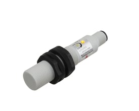 Carlo Gavazzi kapacitiv M18-aftaster med hvid gevindskåret krop, sorte monteringsmøtrikker og gul indikatorlampe.