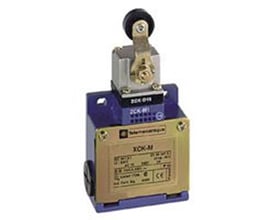 Sidevisning af Schneider Electric XCK-M endestop i metal, viser label med tekniske specifikationer og drejehoved med rulle.