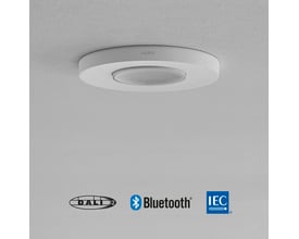 Niko P46MR DALI tilstedeværelsessensor til indbygning i hvid, vist monteret på et lyst loft med DALI, Bluetooth og IEC logoer.