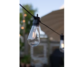 Nærbillede af en Markslöjd ST64 pære fra Garden 24 lyskæden, viser dens transparente glas og glødetråd.
