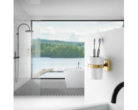 Smedbo house vægmonteret tandglas i hvid porcelæn med poleret messingholder, monteret på væg i badeværelse med udsigt over vand og skov.