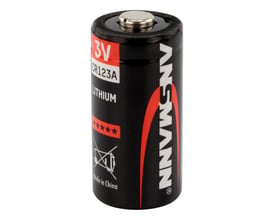Nærbillede af Ansmann CR123A 3V lithium batteri med sort baggrund, viser positive og negative poler, samt advarselssymboler.