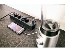 Brennenstuhl Ecolor forlængerledning i sort med fire stikkontakter og to USB-porte, forbundet til en smartphone og blender.
