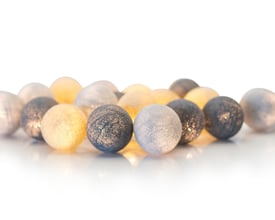 Klar close-up af IrisLights lyskæde med stofkugler i greige nuancer, fremhæver tekstur og farvespil i det varme LED-lys.