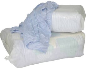 To store hvide plastposer med kulørte blandede pudseklude, ca. 25 kg i alt, med en lys blå klud på toppen.