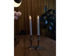 Nærbillede af et hvidt Veli Line 3D kronelys med bevægelig flamme, på en træoverflade.