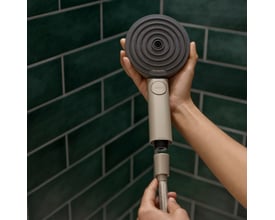 Hænder der samler en beige Hansgrohe håndbruserslange på 1,6 meter med et gråt håndbruserhoved med SELECT-knap.