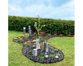 ECCO Products Core Edge kantskinne skaber en flot kant omkring et blomsterbed med barkflis og dekorationer i en have.