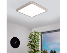 EGLO Fueva-Z loftlampe monteret på et lyst loft i et moderne rum med et ur og en grøn plante.
