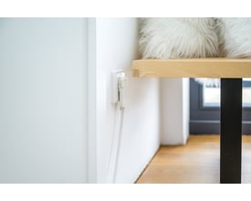 Hvid Brennenstuhl-forlængerledning på 2 meter med jordet, fladt vinkelstik og stikdåse, tilsluttet bag et bord.