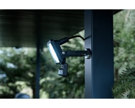 Brennenstuhl 20W LED projektør med sensor monteret på en mørkeblå stolpe, oplyser et udendørsområde.