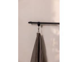 Metallbude Vana håndklædestang i sort metal med rund profil, med en gråvaskeklud hængende på en krog, monteret på en lys væg.