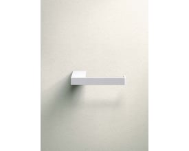 Metallbude Tuali toiletrulleholder i hvid metal, monteret på en lys væg med let tekstur.