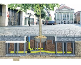 Illustrations viser et GreenMax karm/rist til rodvanding monteret i byen, med jord, rør og et træ.