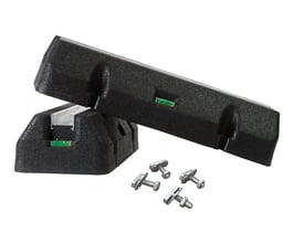 To sorte montagefødder af gummi til varmepumper, hver med et integreret vaterpas, og fire gevindbolte til montering, vist på hvid baggrund.