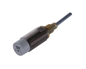 Carlo Gavazzi induktivaftaster M18 med kort, forniklet messinghus, grå front og fast kabel, set skråt forfra.