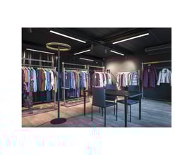 SLV One Straight FL standerlampe i sort og messing med en rund lyskilde, opstillet i et moderne butiksmiljø.