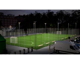 Ansell Lighting Aztec projektør oplyser en fodboldbane om natten med et parkeret hvidt varevogn i forgrunden.