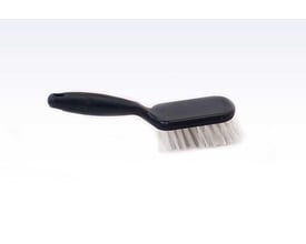 Roliba spandebørste i sort plast med stive, hvide nylonfibre og ergonomisk håndtag på hvid baggrund.