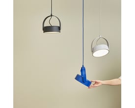 En hånd holder Hübsch Stage loftlampen i blå metal ved siden af to andre Stage lamper i grå og hvid.