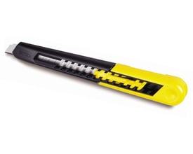 Detaljebillede af Stanley 9 mm kniv, der fremhæver det sorte greb med gul bladmekanisme og serrateret skinne.