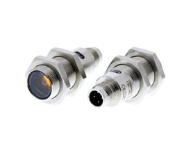 Omron fotoaftaster M18 i rustfrit stål, visende gevindet og M12 stikket på et objekt.