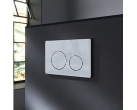 AM.PM X-Joy S toiletsætets hvide trykplade med to runde betjeningsknapper ses monteret på en mørk væg ved siden af et vindue.