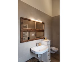 SLV Glenos 60 LED spejllampe monteret over et rustikt spejl på en badeværelsesvæg, giver jævn belysning.