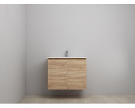 Sanibell Online møbelsæt i bardolino eg med to grebsfrie låger og en hvid porcelænsvask med armatur, monteret på en grå væg.