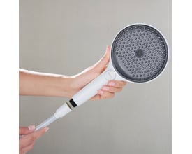 Person holder en Hansgrohe håndbruser med hvidt greb, mens den hvide bruserslange med tekstilflet er tilsluttet.