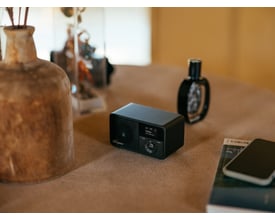 Sangean DDR-7X sort DAB+/FM-radio med trækabinet står på et bord med dekorationer.