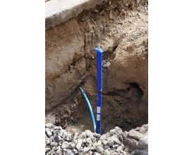 Isiflo teleskopisk stikledningsgarniture monteret i en udgravning, tilsluttet et blåt rør og klar til brug.