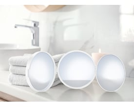 Smedbo outline lite rejsespejl i mat hvid, med tre runde spejloverflader, står på en bordplade ved siden af et foldet håndklæde og et stearinlys.