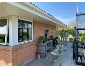 Plastmo hvid tagrende på 3 meter monteret på et murstenshus med en person i drivhus i baggrunden.