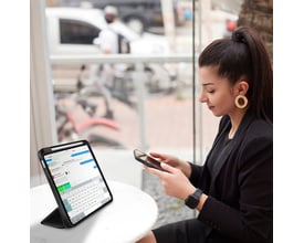 Kvinde bruger 4smarts Folio Case Basic til iPad på en café, med pen og telefon ved siden af.