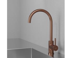 Lavabo Primy Curve køkkenarmatur i ravfarvet kobber, monteret ved en stålvask i et moderne køkkenmiljø.