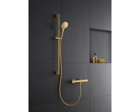 Duravit håndbruser i poleret guld med 3 stråletyper, monteret på en mørkegrå væg ved siden af en sæbedispenser og svamp.