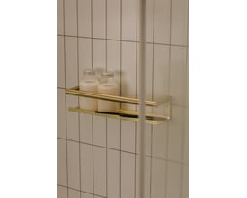 Cosmic brusehylde i børstet guld med to flasker og en glasvisker, monteret på flisevæg.