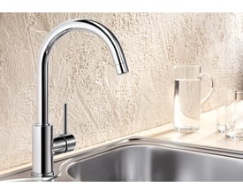 Blanco Mida køkkenarmatur i krom med C-tud og 1-grebs betjening monteret på en stålvask.